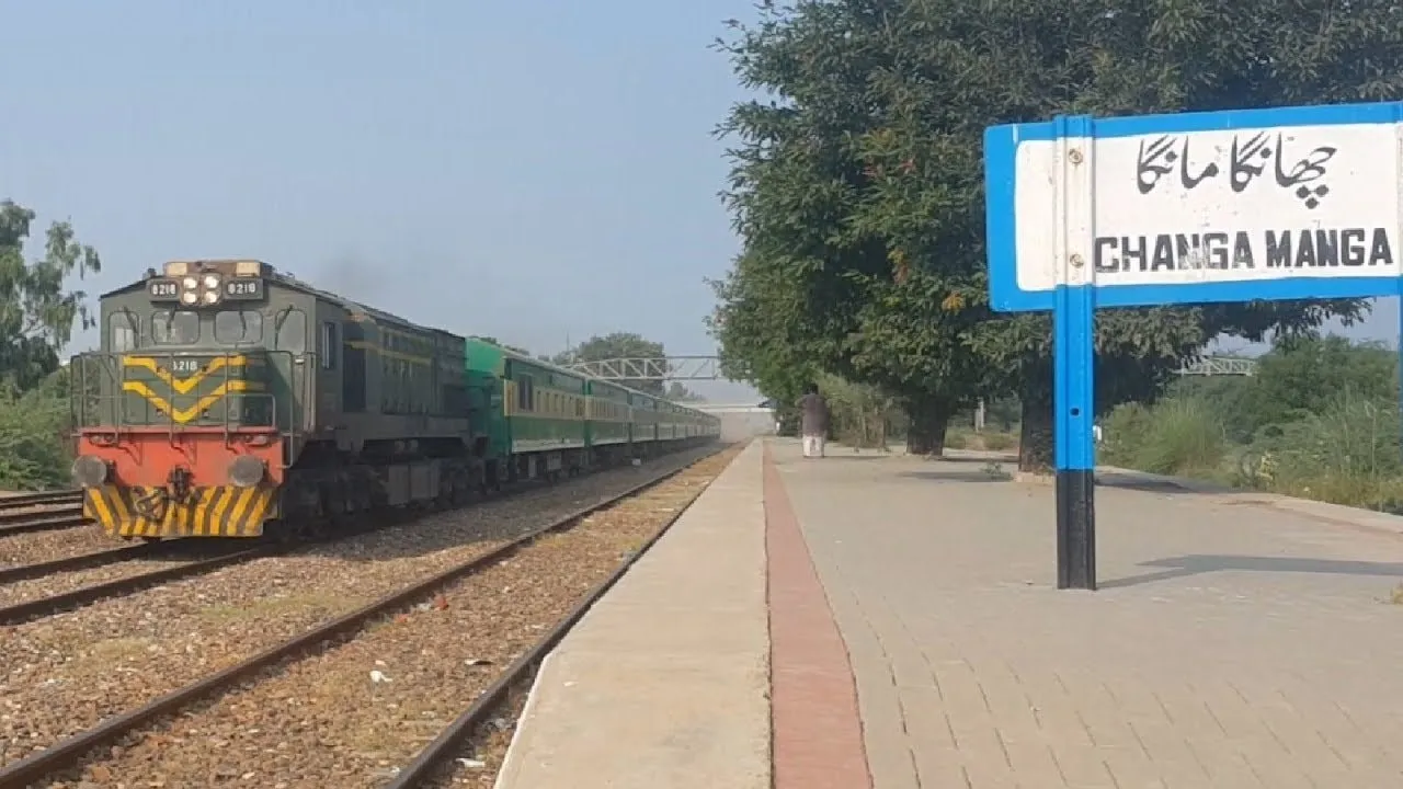 A Pakistan Railways mainline train arriving at Changa Manga railway station, the station nameboard visible beside the track